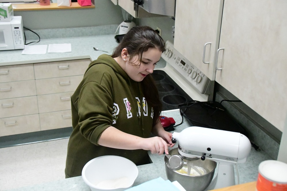 CMS Baking Elective - Student adds dry ingredients to the mixing bowl